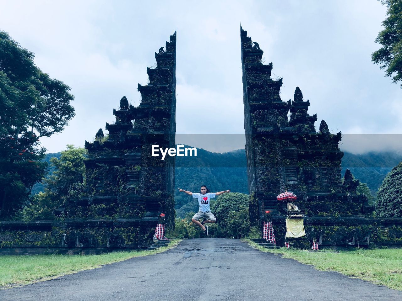 Man levitating over road against old ruins of temple