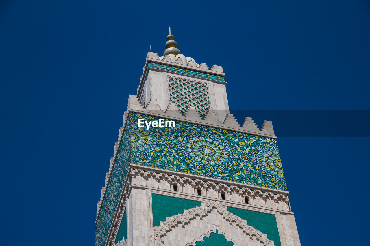 Low angle view of hassan ii mosque tower against blue sky - casablanca, morocco 