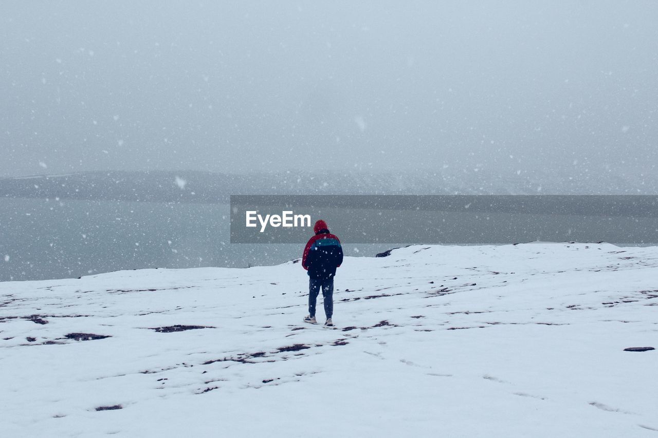 Rear view of woman walking on snow covered landscape