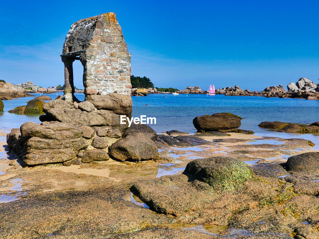 Rock formation on beach against blue sky