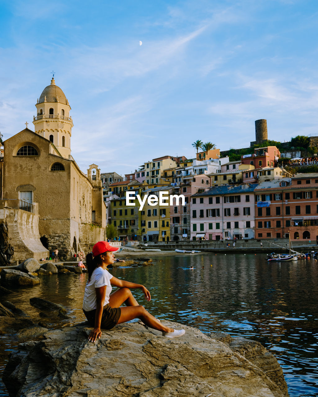 FULL LENGTH OF WOMAN STANDING ON CANAL AMIDST BUILDINGS AGAINST SKY