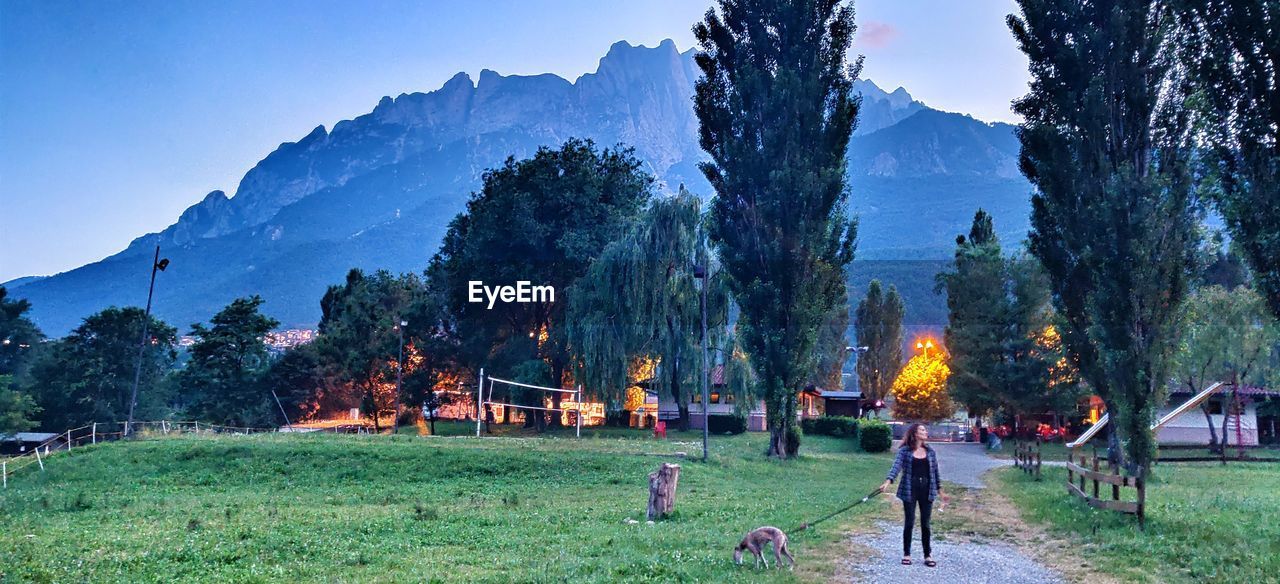 GROUP OF PEOPLE ON FIELD AGAINST TREES