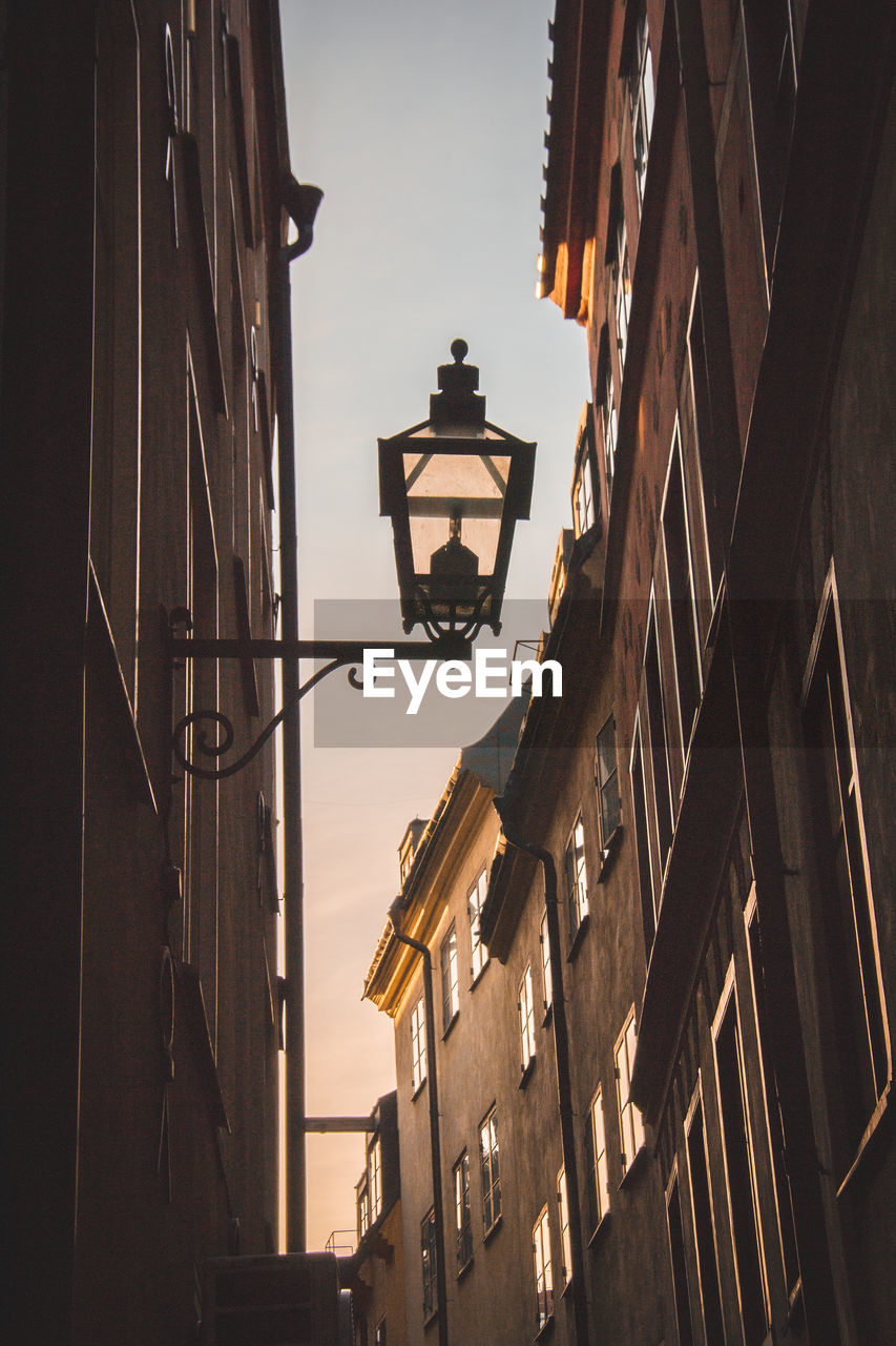 LOW ANGLE VIEW OF ILLUMINATED STREET LIGHT AGAINST BUILDINGS