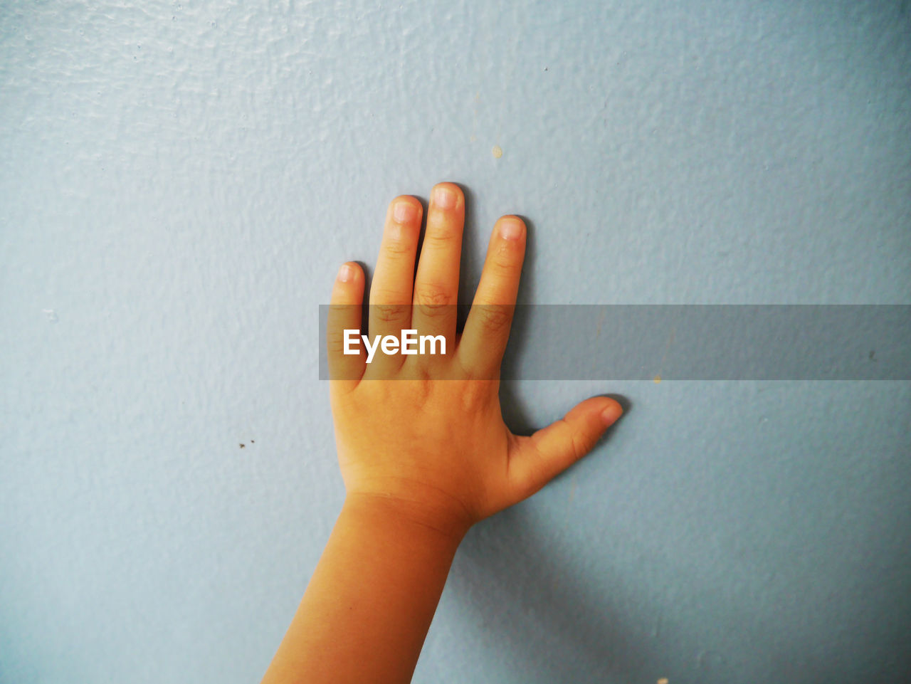 CLOSE-UP OF HUMAN HAND AGAINST WALL