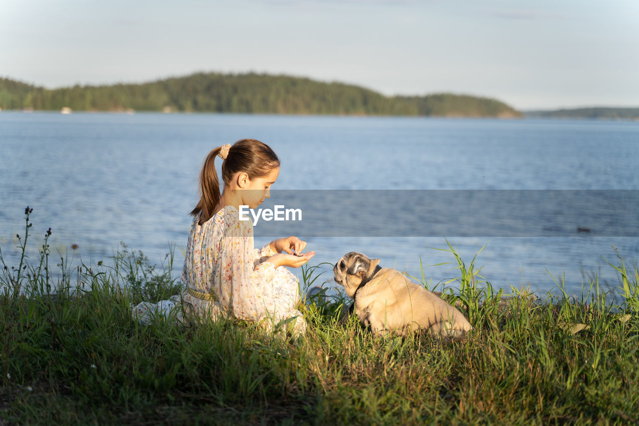 A girl and a pug on the lake shore