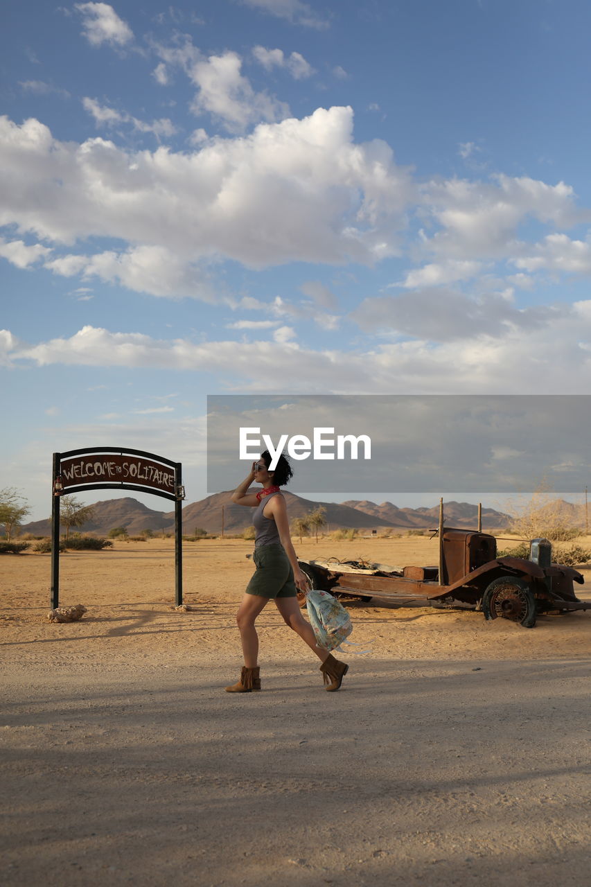 Full length of woman walking on road against sky