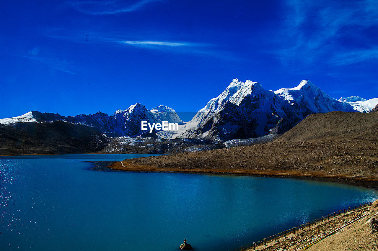 SNOWCAPPED MOUNTAINS BY LAKE AGAINST BLUE SKY