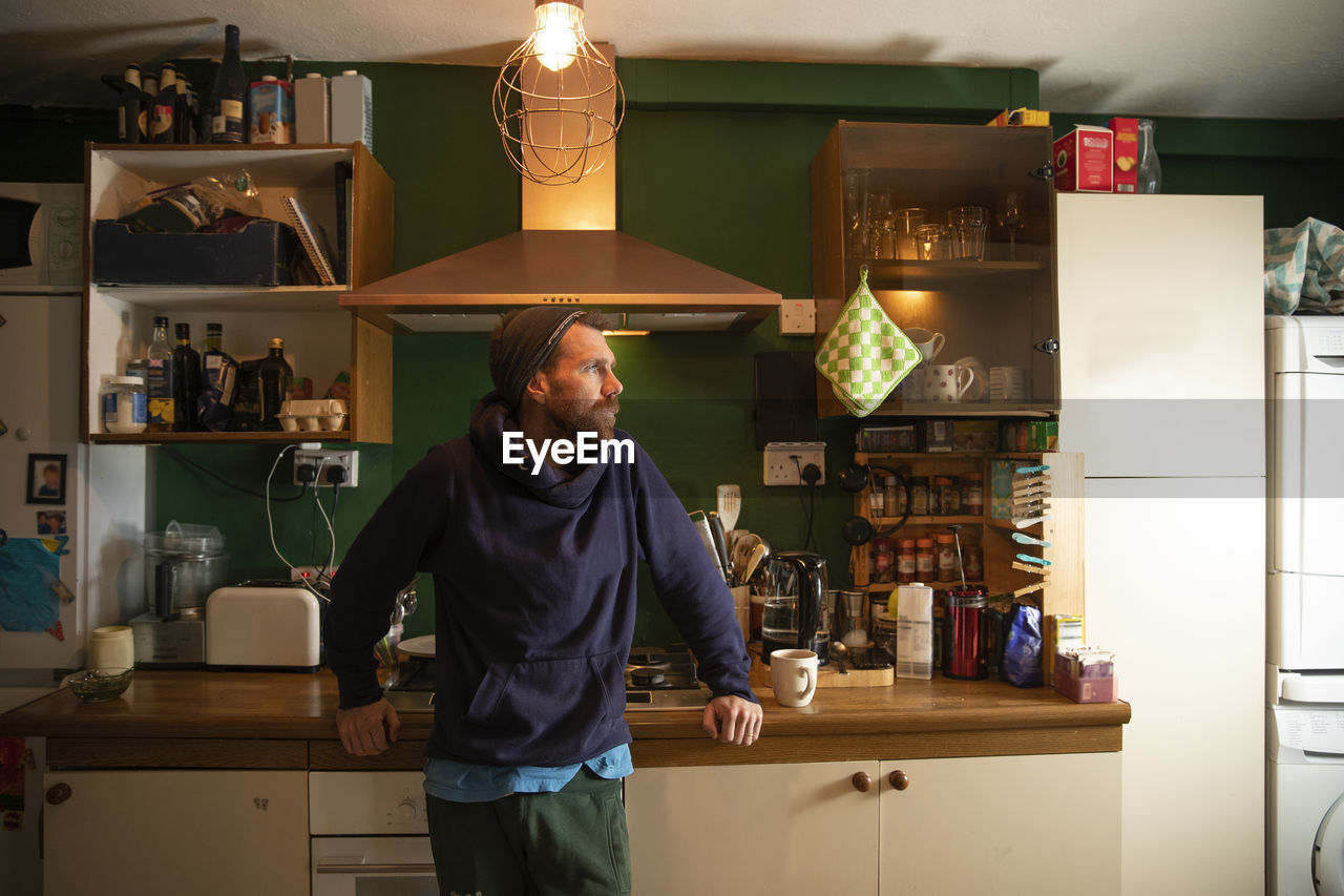 Man standing in illuminated kitchen at home