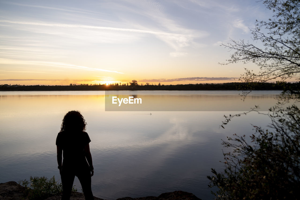 Traveler woman walking by the lake during sunset.