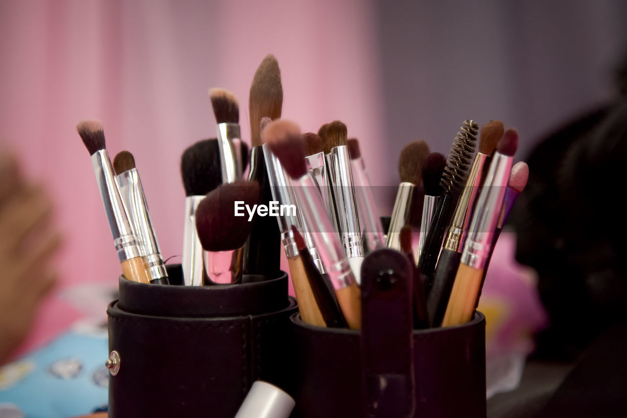 cosmetics, make-up brush, make-up, brush, hand, indoors, beauty product, pink, large group of objects, close-up, focus on foreground, variation, fashion, human eye, paintbrush, purple, arts culture and entertainment