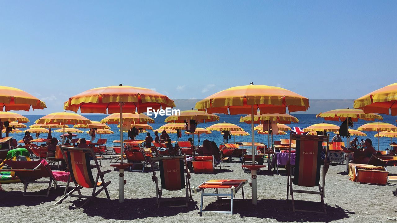 Chairs and parasols on beach against clear blue sky