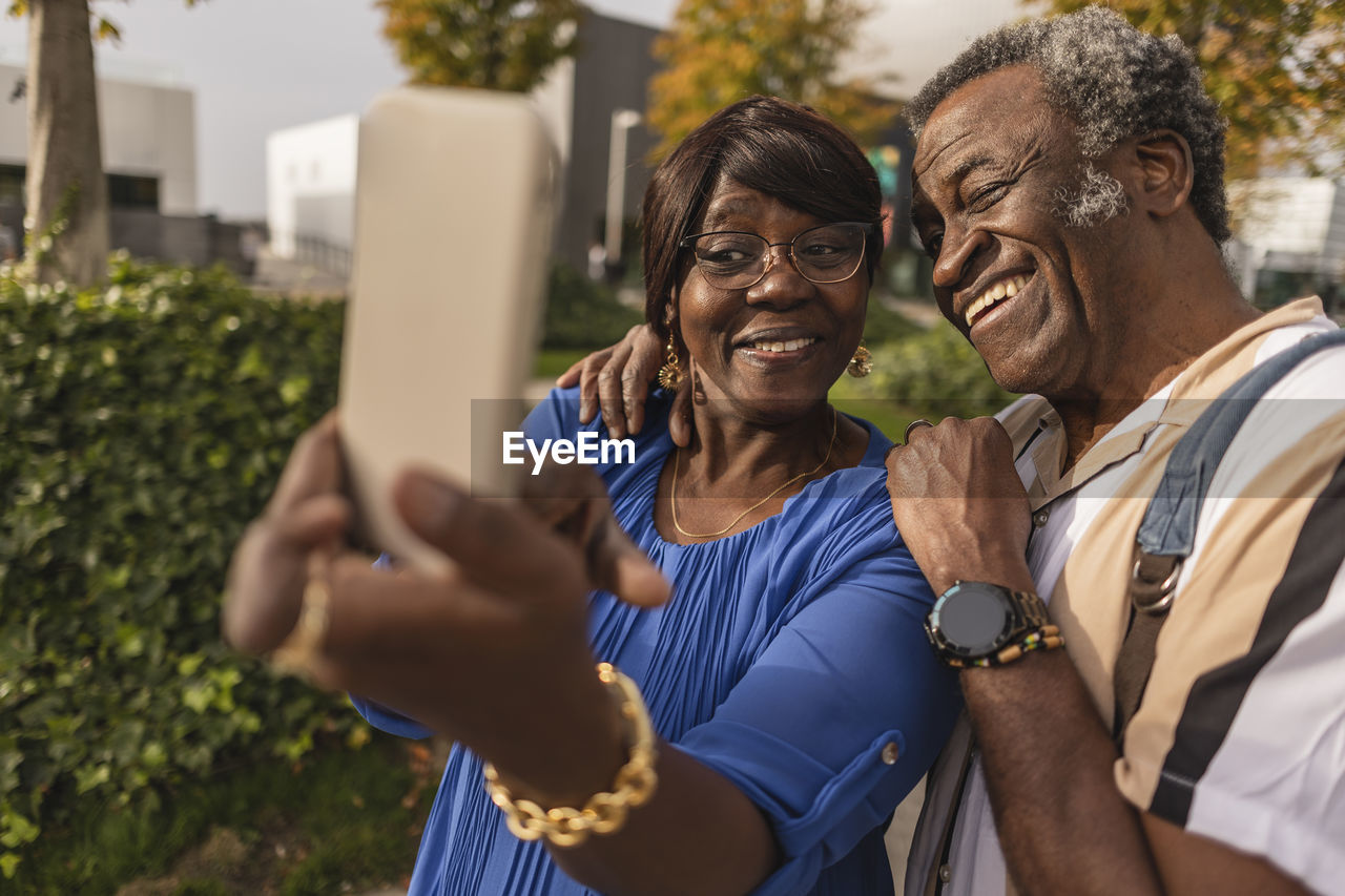 Happy senior couple taking selfie through smart phone at park