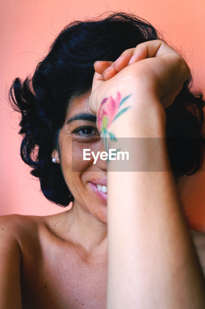 Close-up of smiling woman against wall