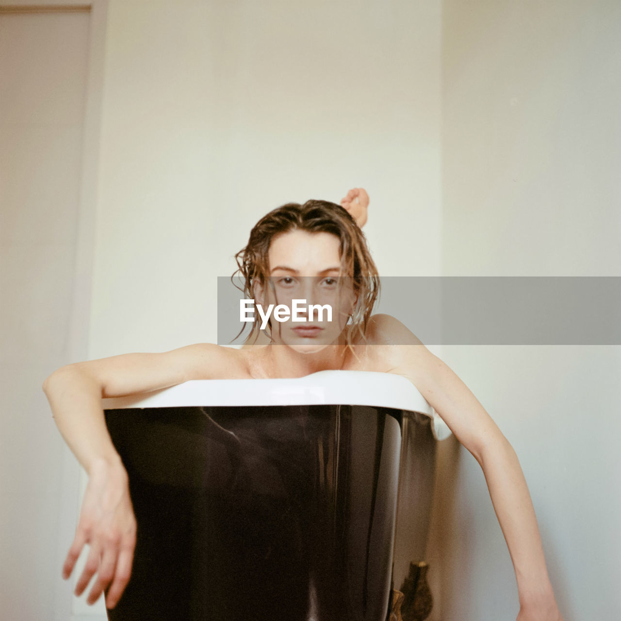 Portrait of beautiful young woman standing against wall at home