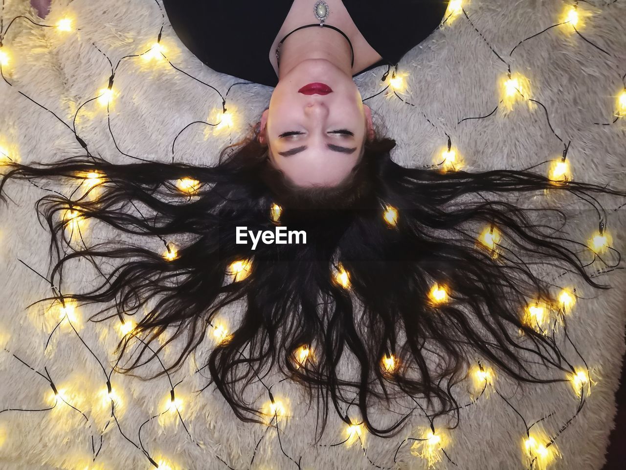 HIGH ANGLE PORTRAIT OF WOMAN WITH ILLUMINATED LIGHTS IN BACKGROUND