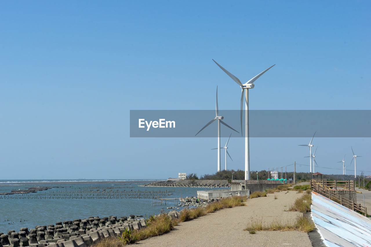 Wind turbines at sea against clear sky