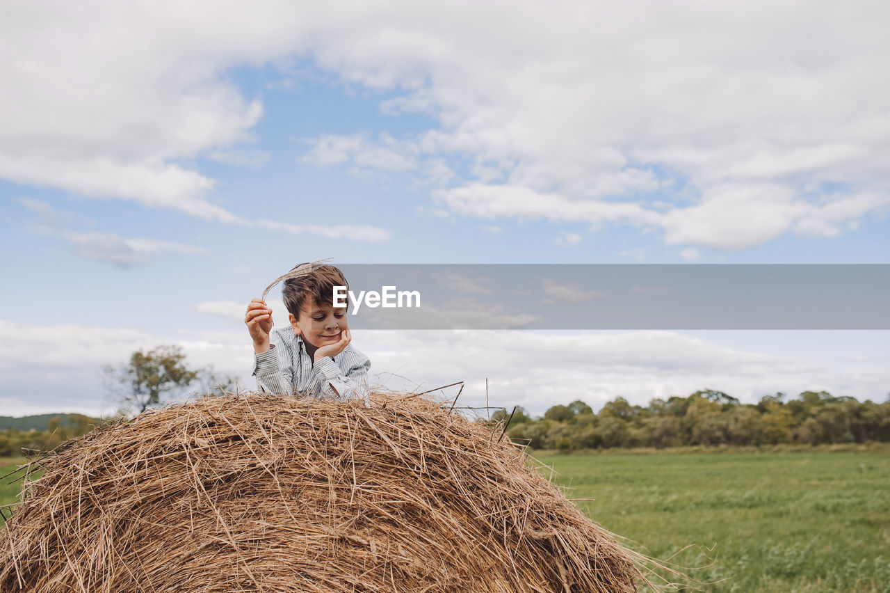 Cute boy sitting on haystack