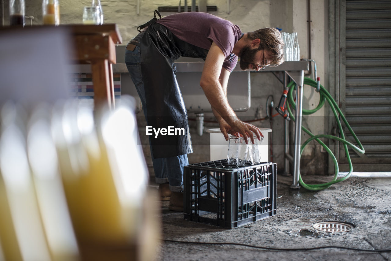 Man placing clean empty glass bottles on crate