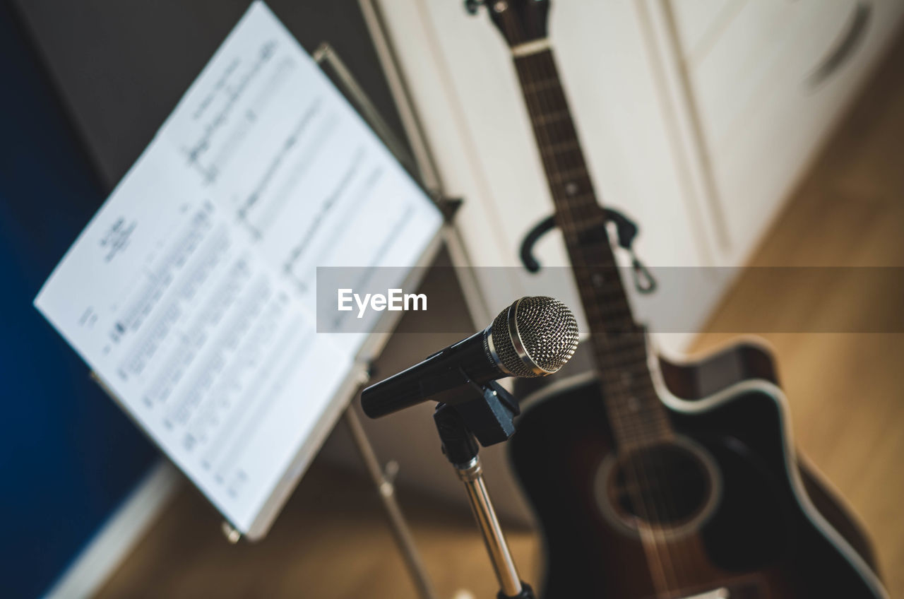 Close-up of microphone with musical note and guitar in background