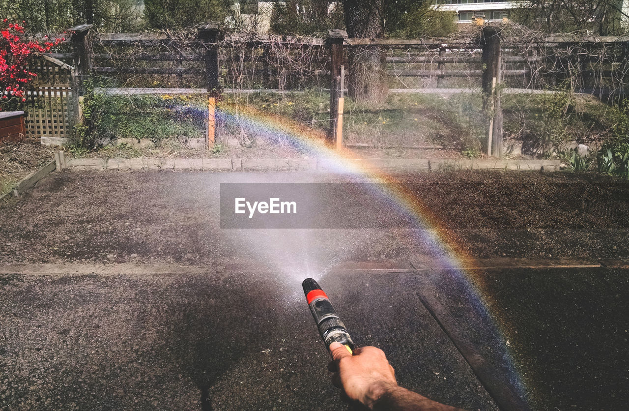 Cropped image of hand sprinkling water on street