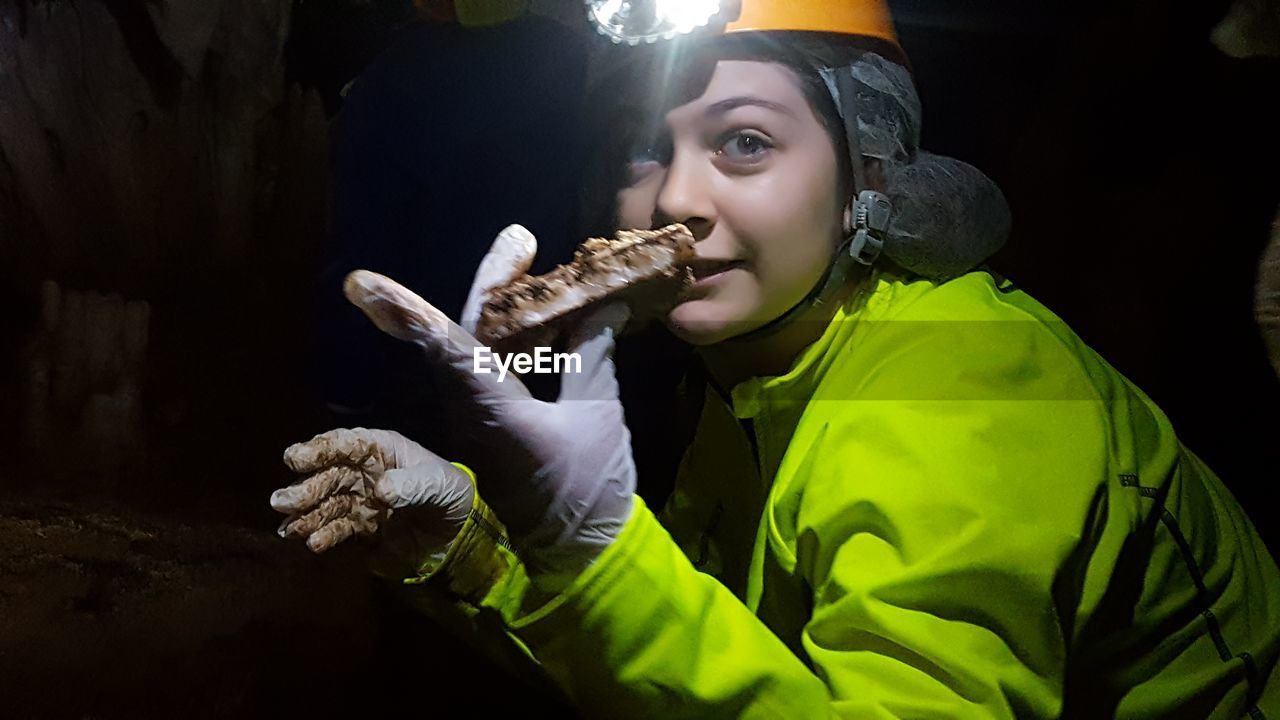 Teenage girl in protective clothing girl holding stone at night