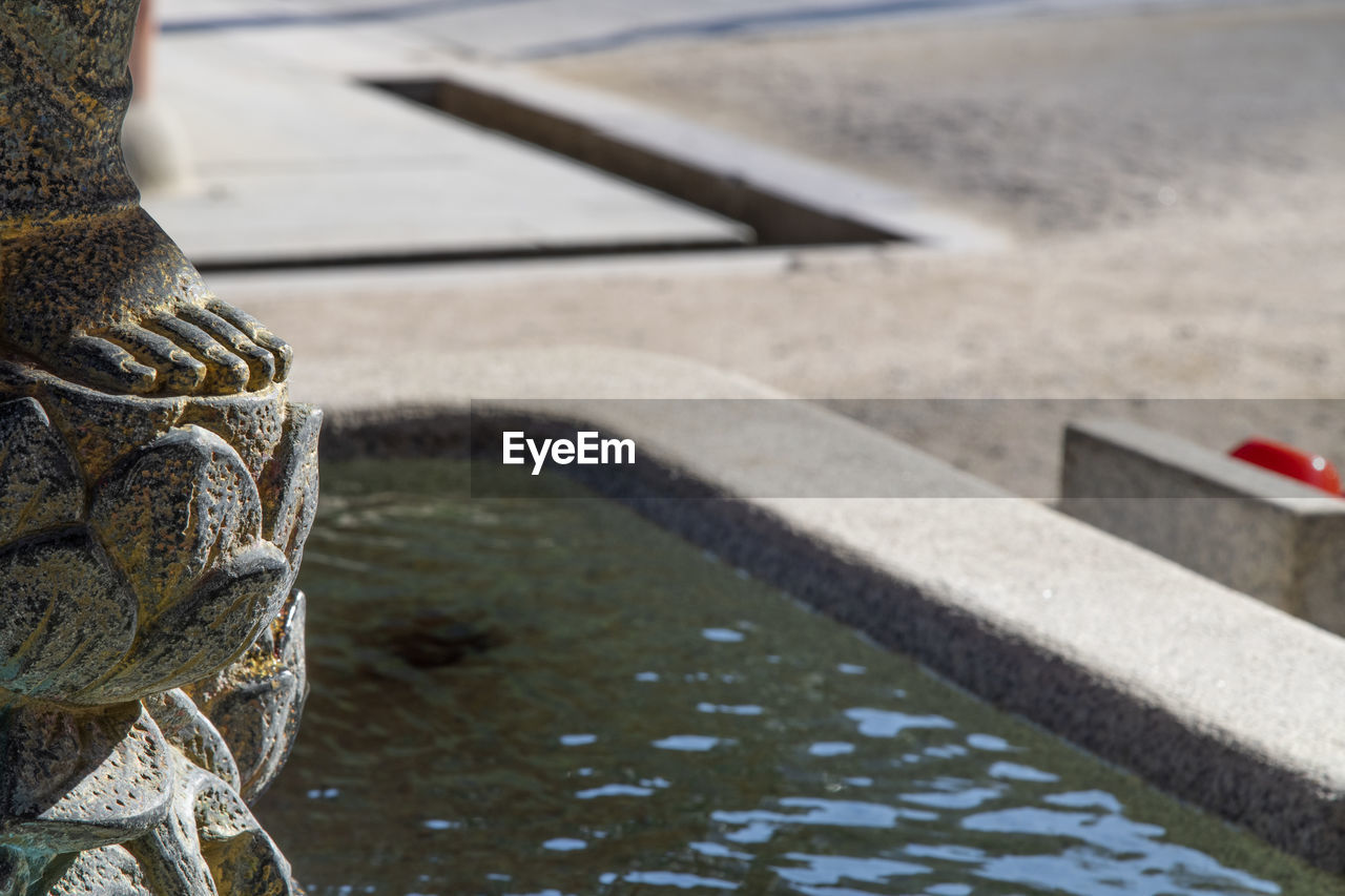 Close-up of buddha statue foot by fountain 