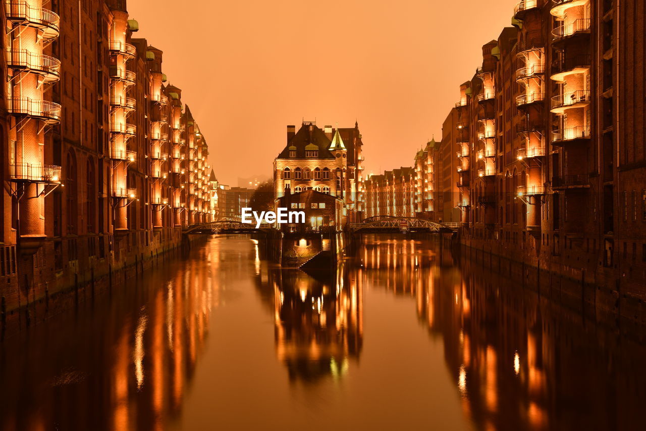 Reflection of buildings in water at sunset