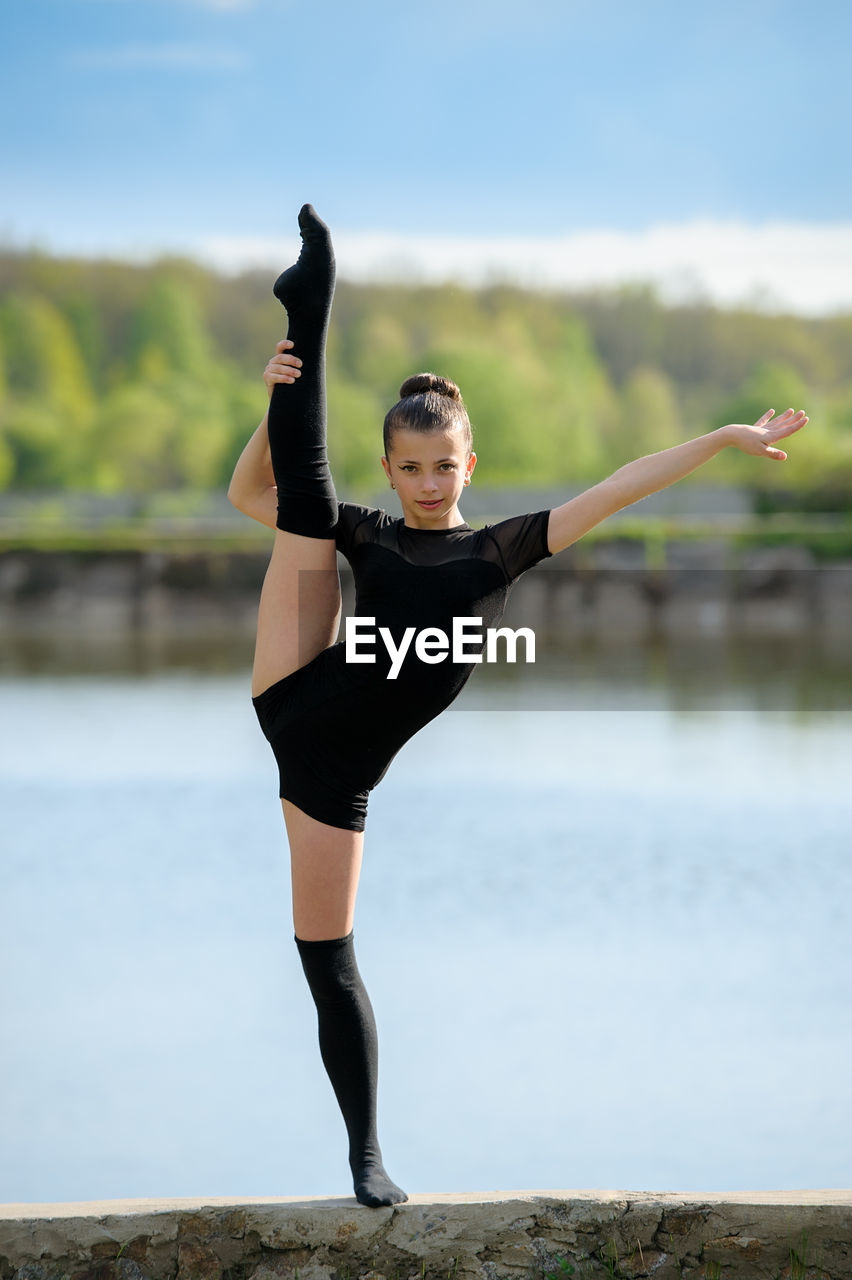 FULL LENGTH OF YOUNG WOMAN JUMPING IN MID-AIR