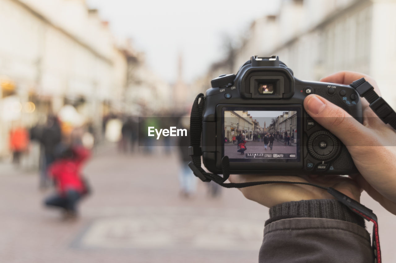 Cropped image of person photographing through camera on street