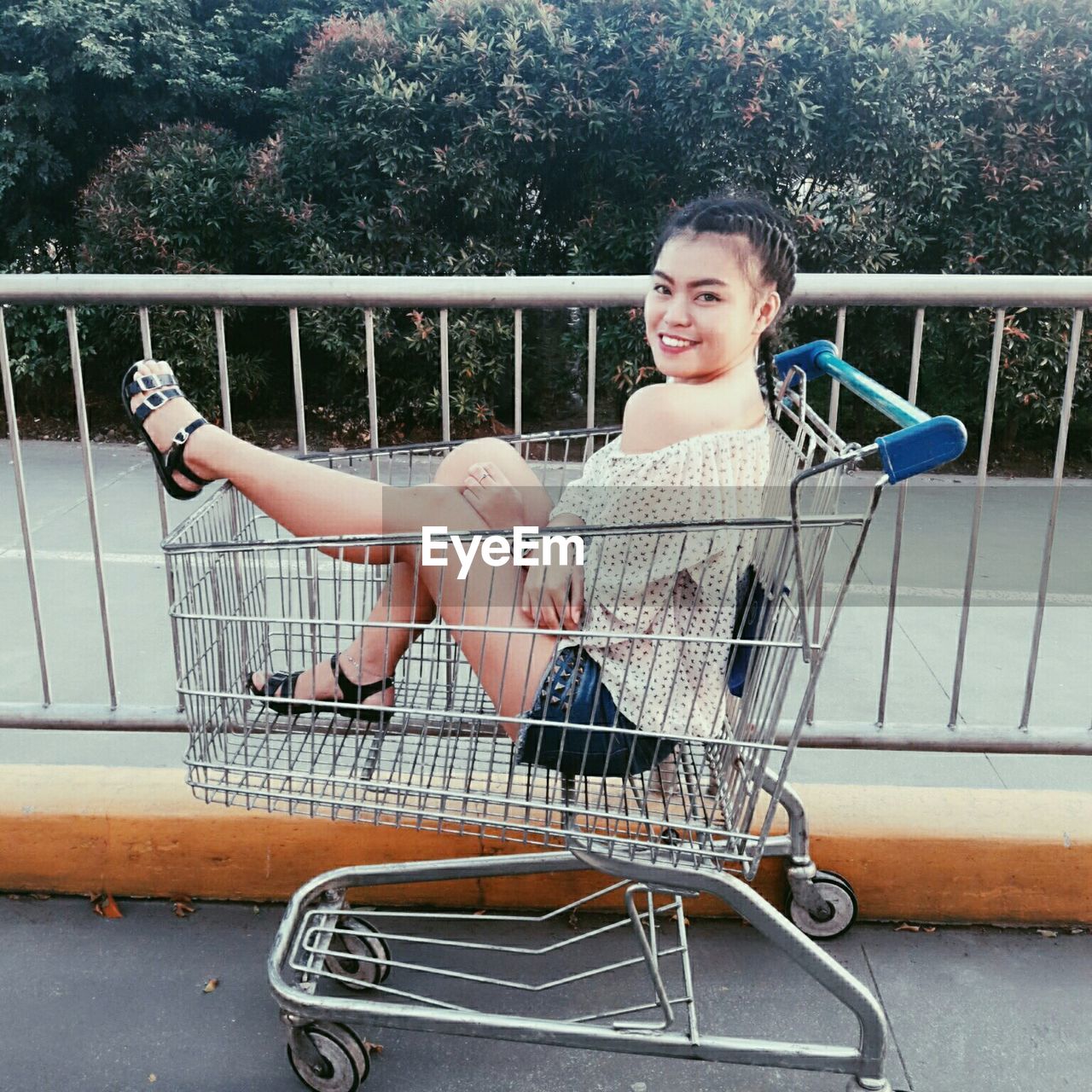 Portrait of woman sitting in shopping cart