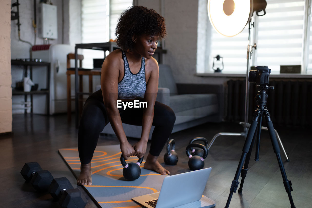 Black coach recording kettlebell exercise for blog