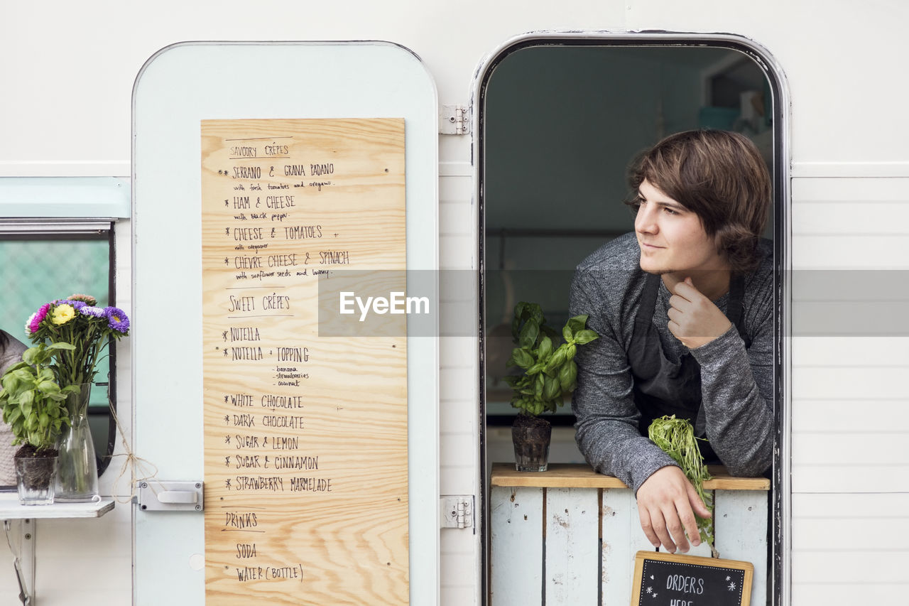 Thoughtful male owner looking out through food truck window