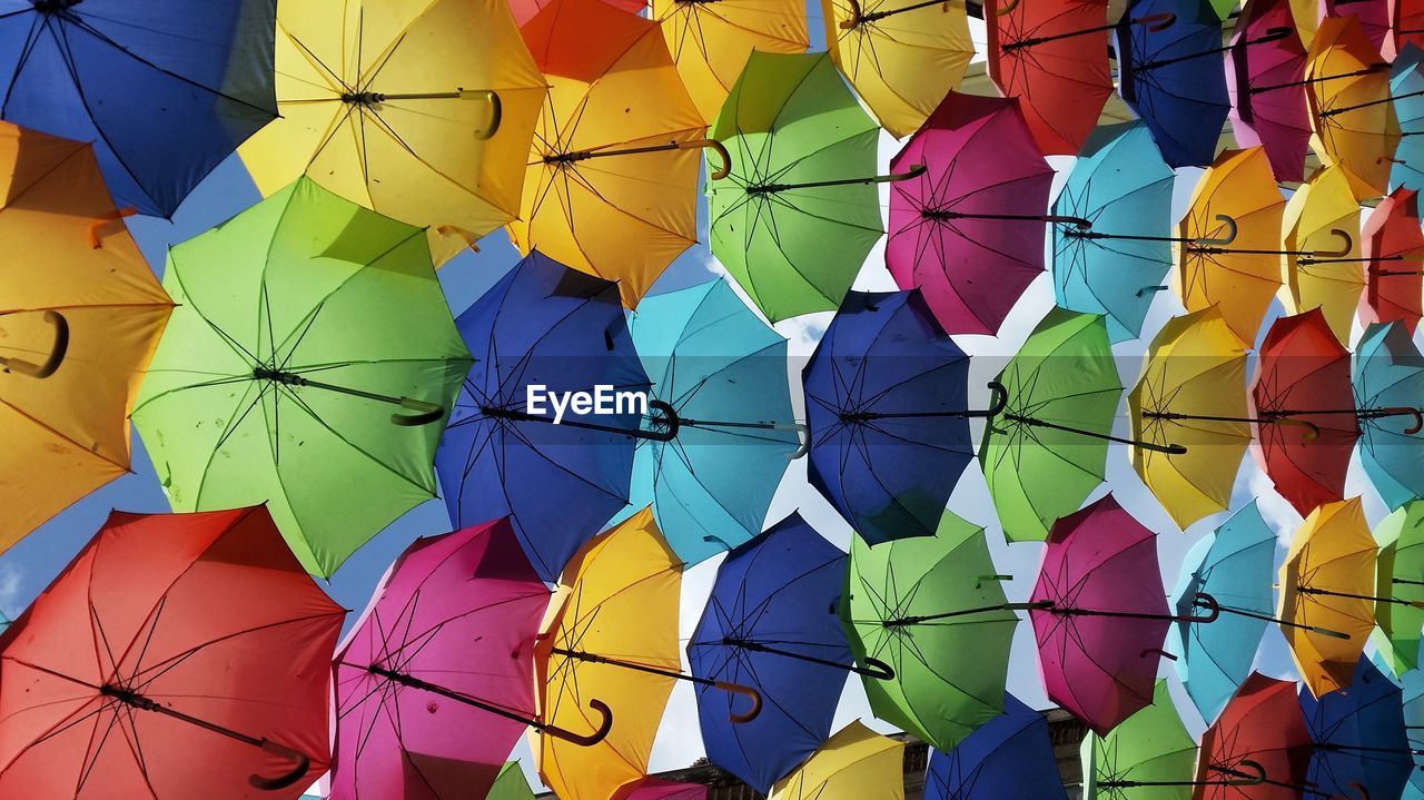 Full frame shot of multi colored umbrellas hanging against sky