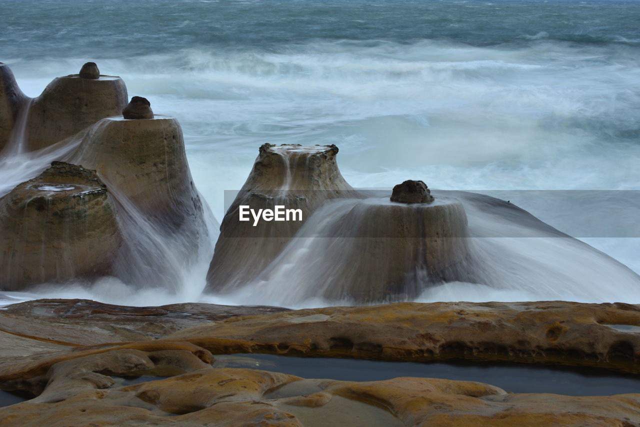 Scenic view of waterfall by sea