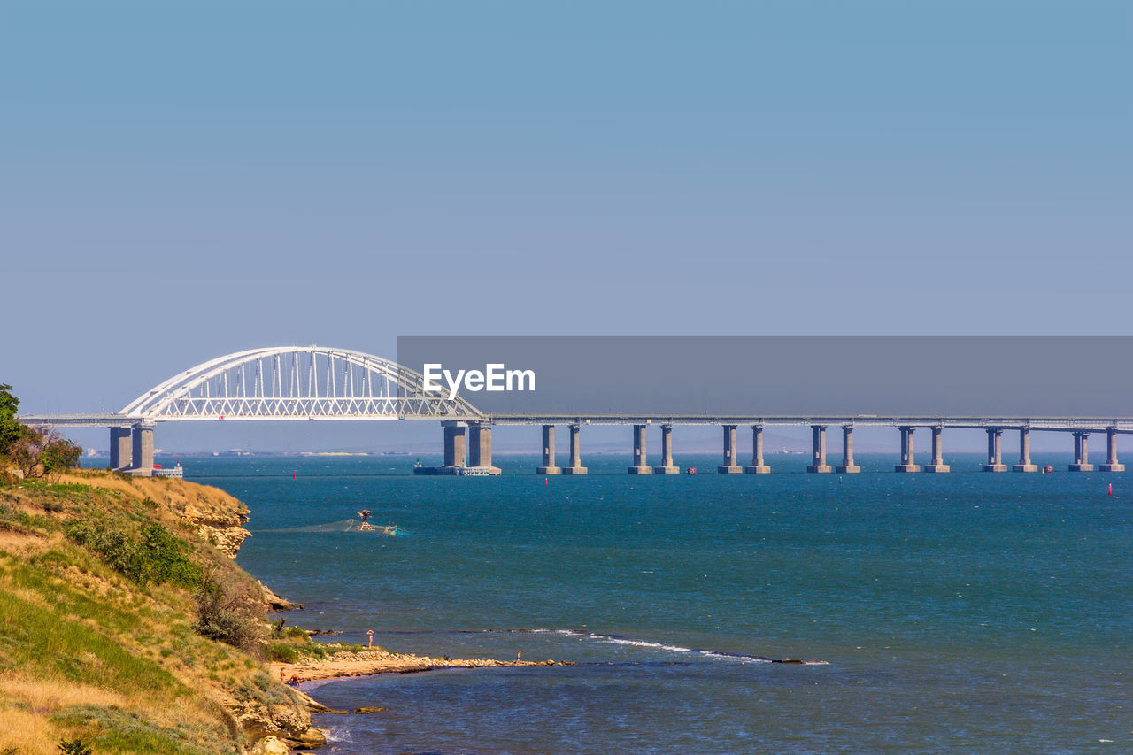 VIEW OF BRIDGE OVER SEA AGAINST CLEAR SKY