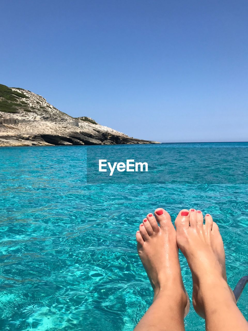 LOW SECTION OF WOMAN LEGS AGAINST BLUE SEA