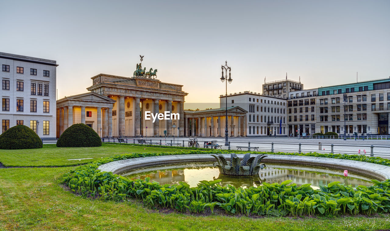 The famous brandenburg gate in berlin after sunset with a fountain