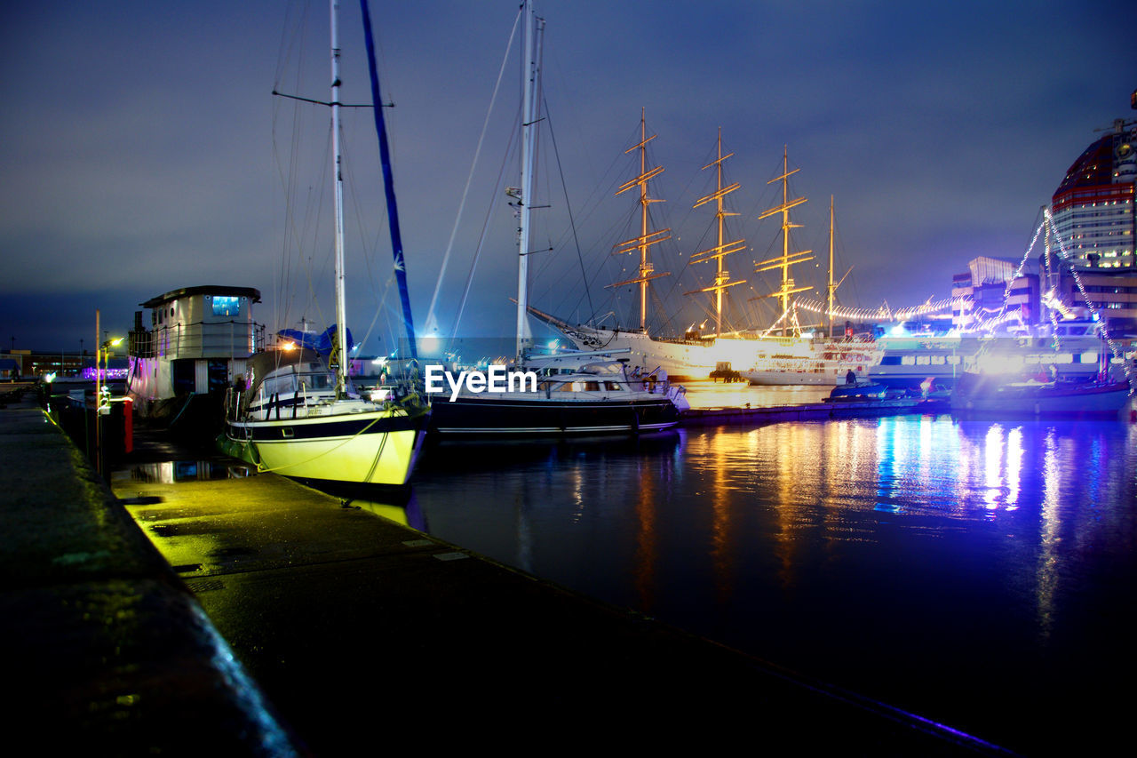 Boats moored in harbor at night