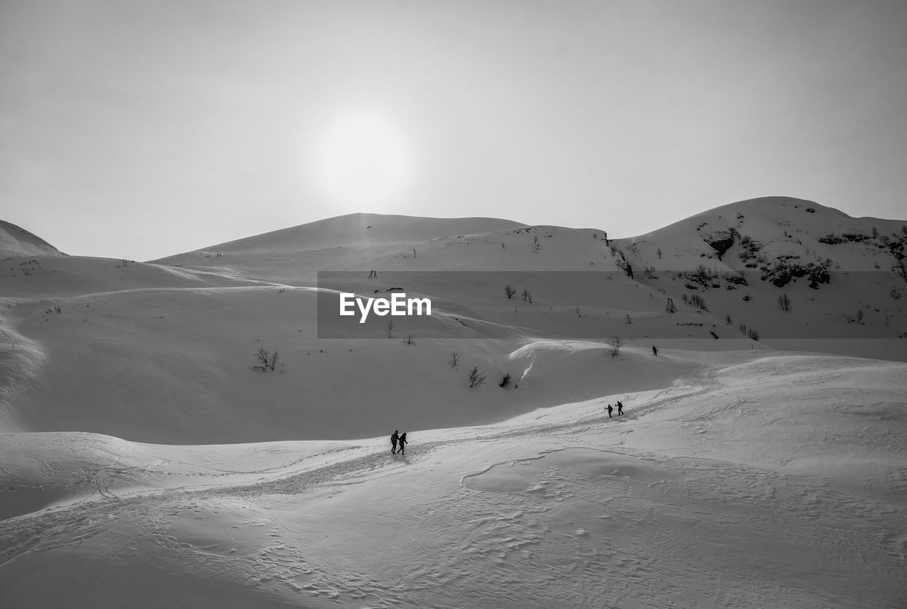 PEOPLE ON SNOWCAPPED MOUNTAINS AGAINST SKY