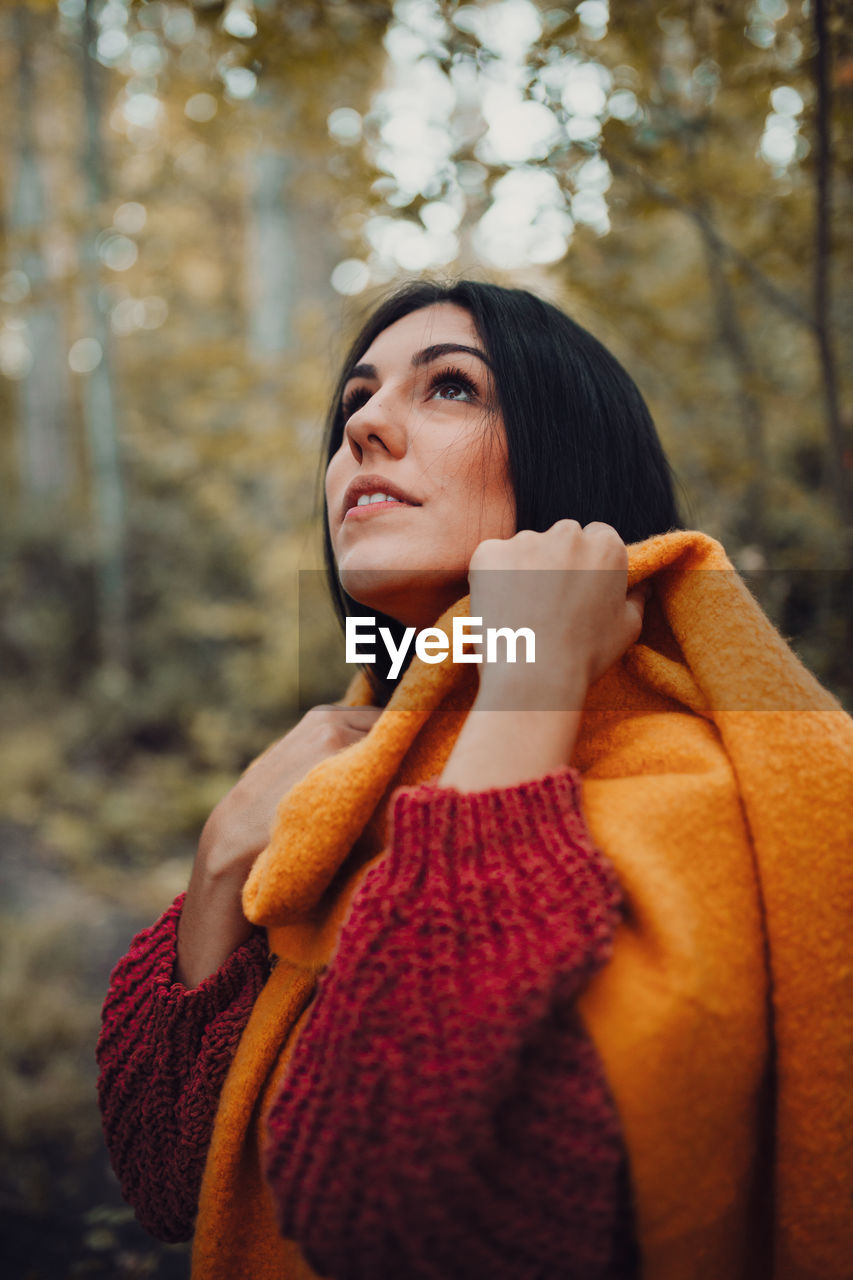 Close-up of young woman looking up standing in forest