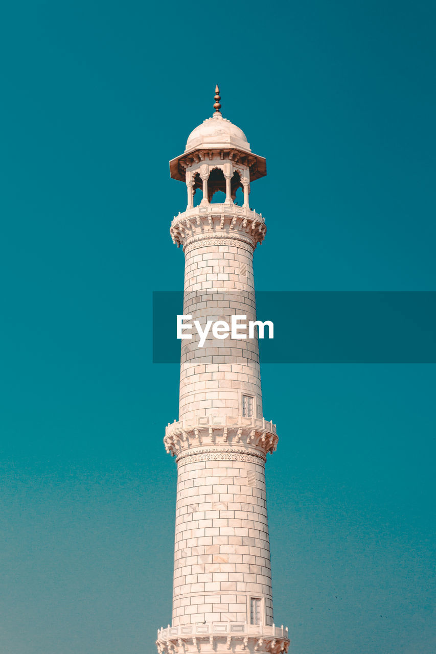 Low angle view of minaret against clear blue sky
