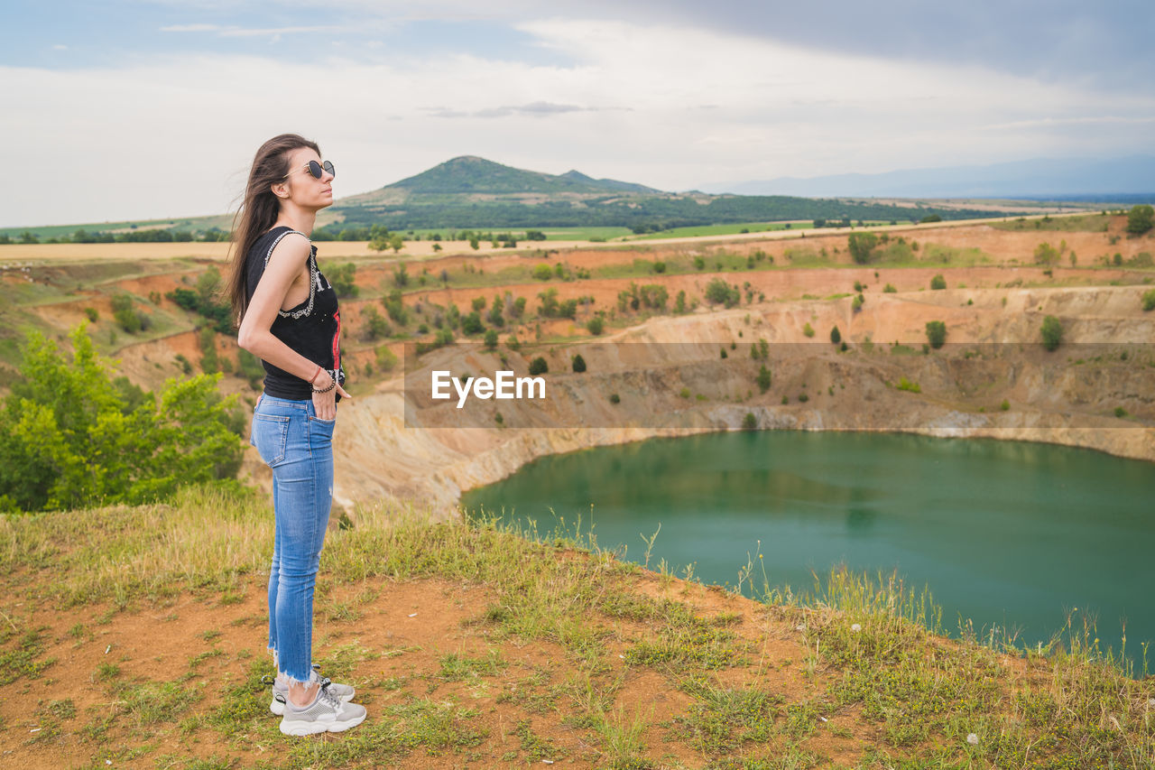 FULL LENGTH PORTRAIT OF WOMAN STANDING AGAINST SKY