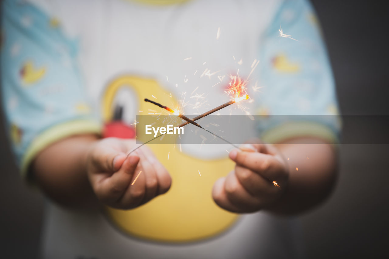 Close-up midsection of boy holding sparklers 