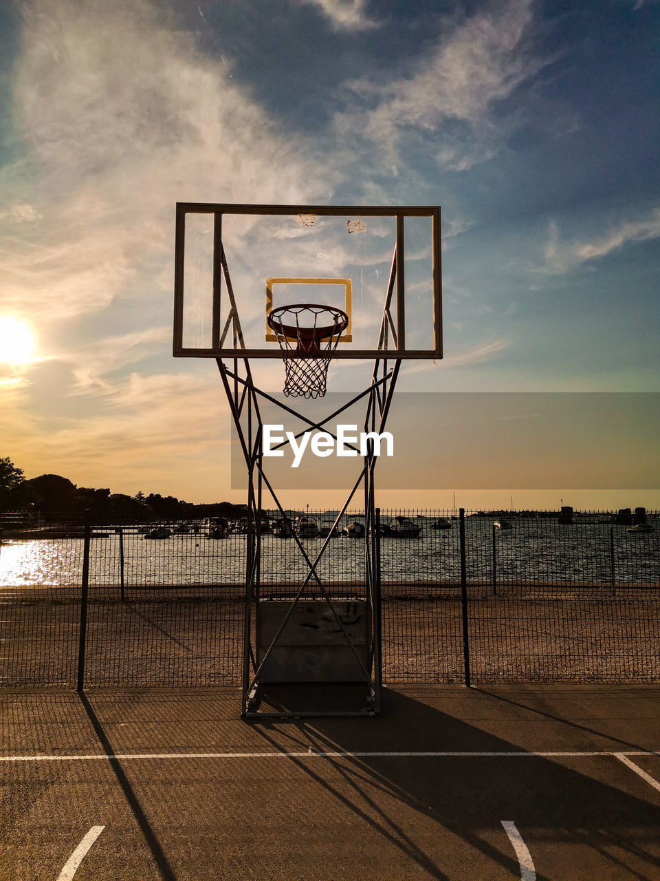 Basketball hoop on beach against sky during sunset