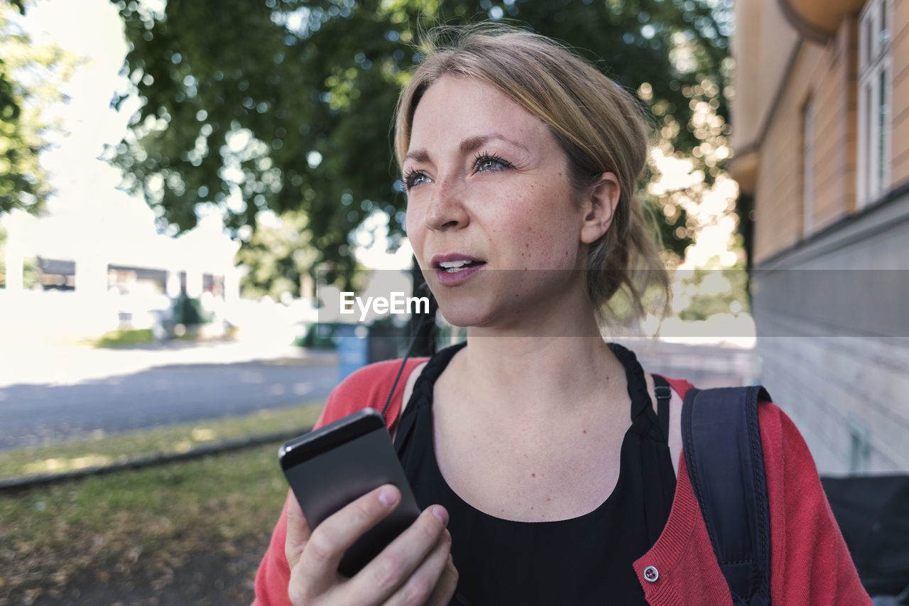 Mid adult woman talking on mobile phone while walking on sidewalk