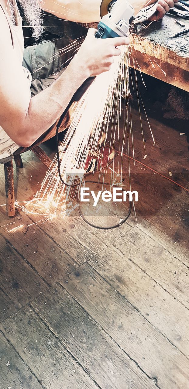 LOW ANGLE VIEW OF MAN WORKING ON WOODEN TABLE