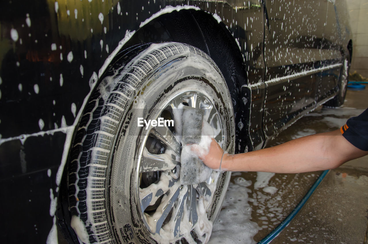 Cropped image of mechanic washing wheel