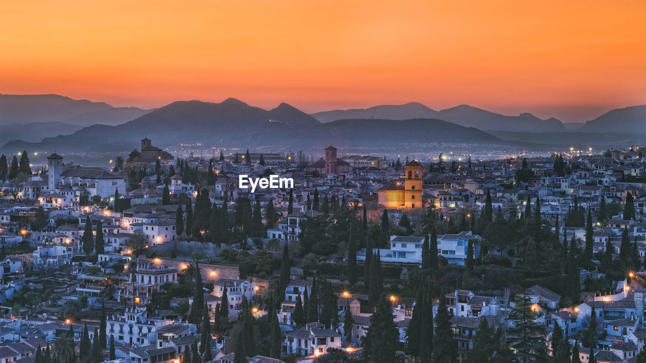 High angle view of illuminated cityscape against sky at sunset