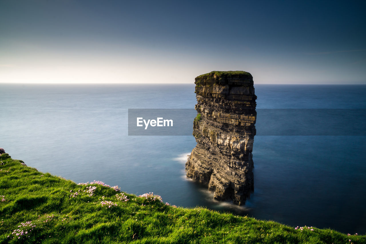 Scenic view of rock formation in sea against blue sky