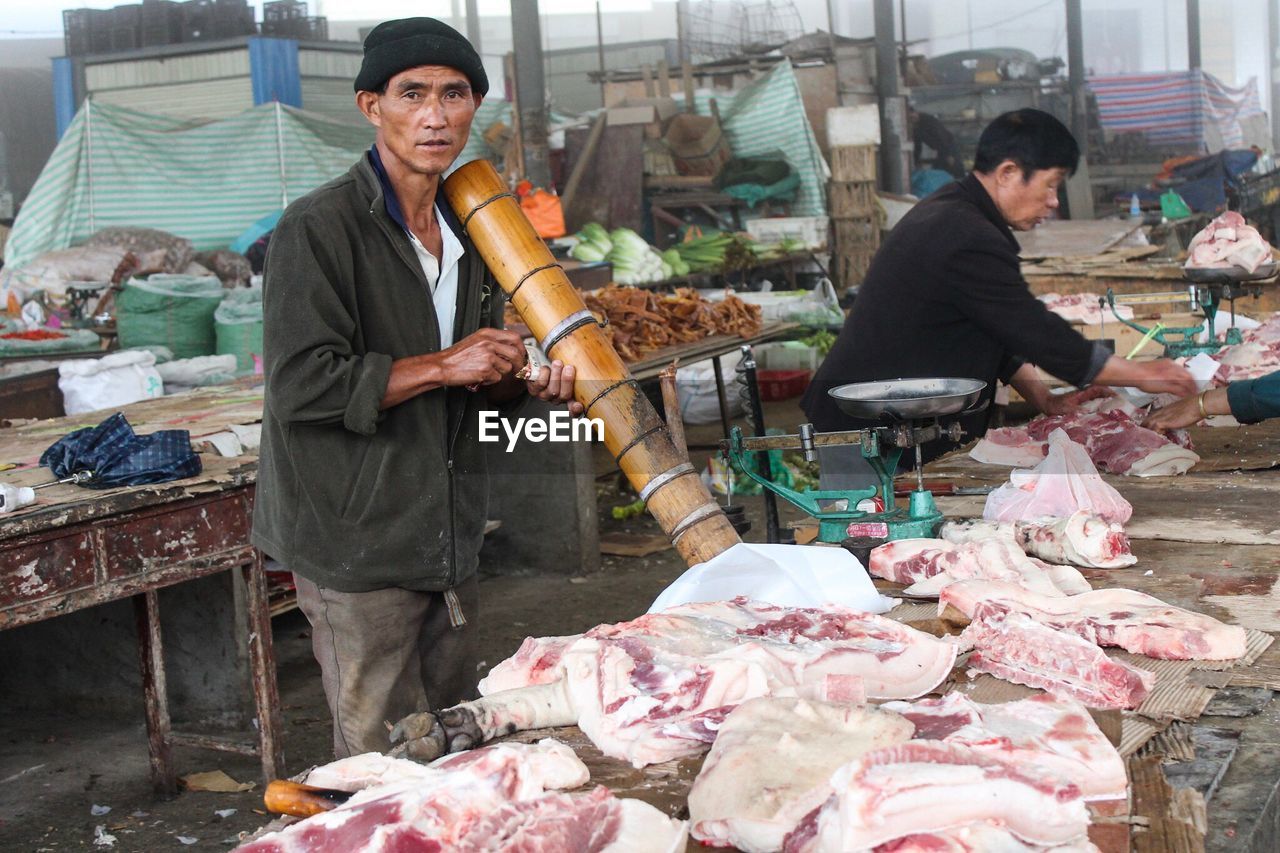 Portrait of butcher selling meat at market